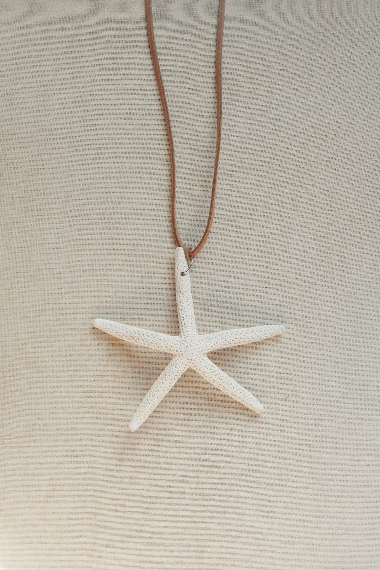 Starfish pendant necklace on a beige background