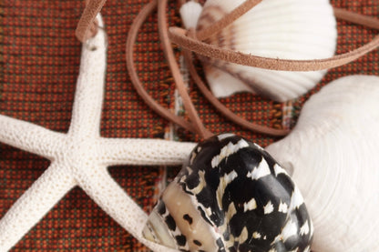 Decorative arrangement with a starfish, shell, and decorative rope on a textured brown surface.