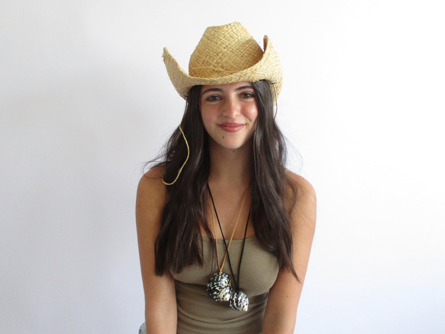 Woman wearing a straw cowboy hat against a plain background