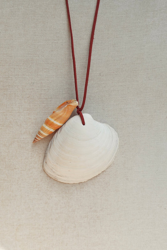 Necklace with a white shell and a small shell pendant on a beige fabric background
